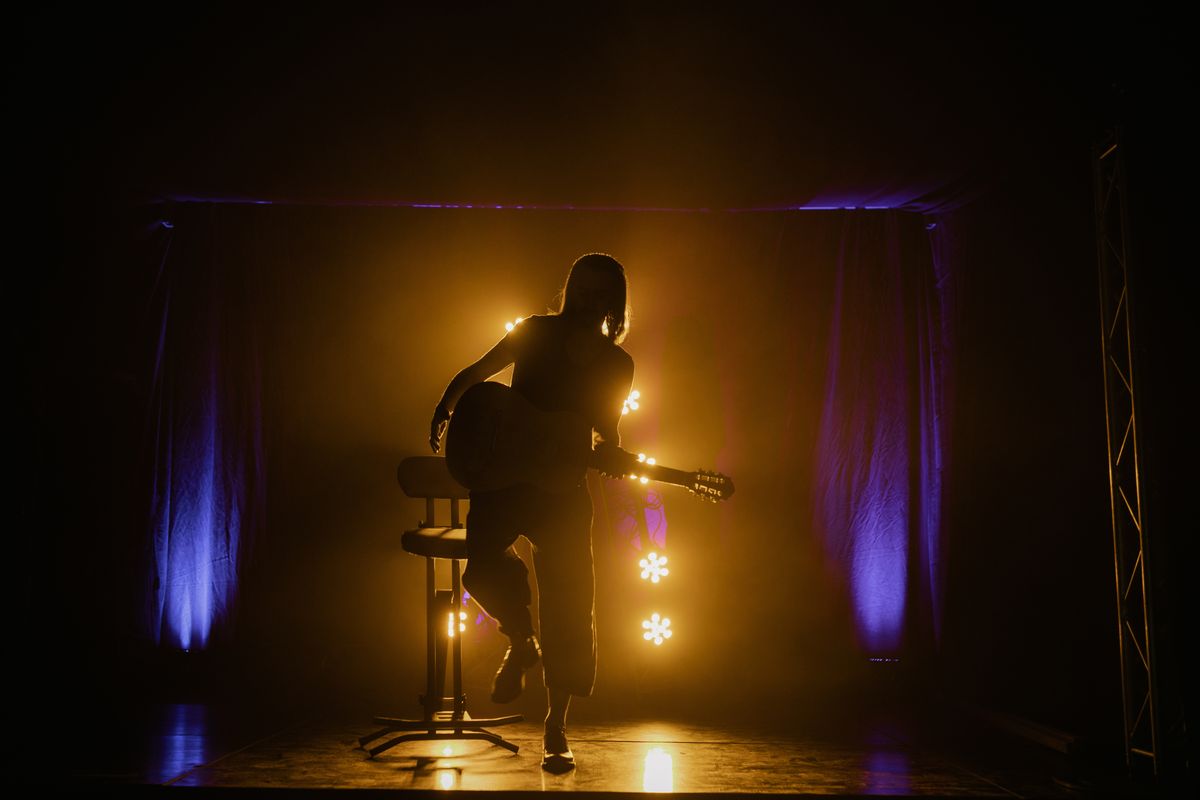 Silueta ilustrativa de una artista con guitarra sobre el escenario